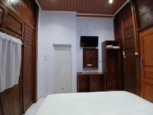 a bedroom with a bed and a tv and a door at D'Bondowoso Homestay Magelang RedPartner in Sumberrejo