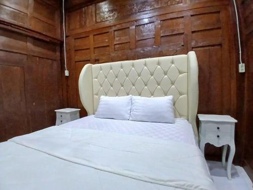 a bed with white sheets and two tables in a room at D'Bondowoso Homestay Magelang RedPartner in Sumberrejo