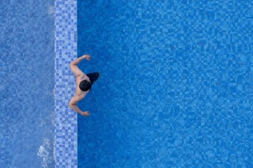 a person swimming in a swimming pool at Amaranta Prambanan Yogyakarta in Yogyakarta