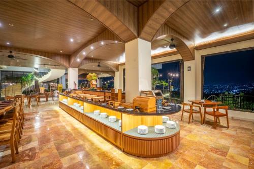 a restaurant with wooden ceilings and tables and windows at Amaranta Prambanan Yogyakarta in Yogyakarta
