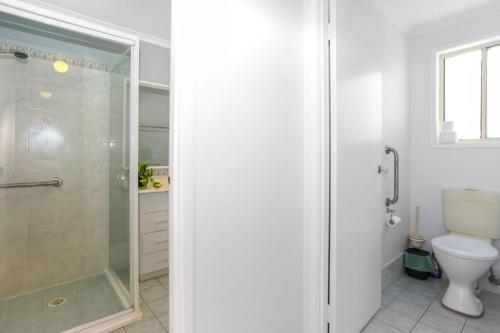 a white bathroom with a shower and a toilet at Saltwater Retreat Hawks Nest in Hawks Nest