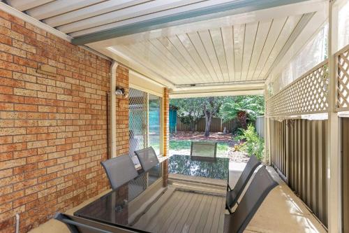 a patio with two chairs and a table and a brick wall at Saltwater Retreat Hawks Nest in Hawks Nest