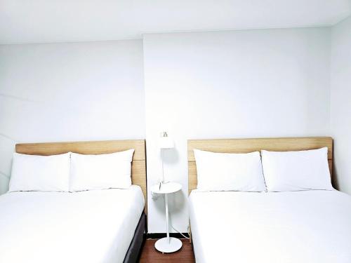 two beds in a bedroom with white walls at Ciel de Mer in Busan