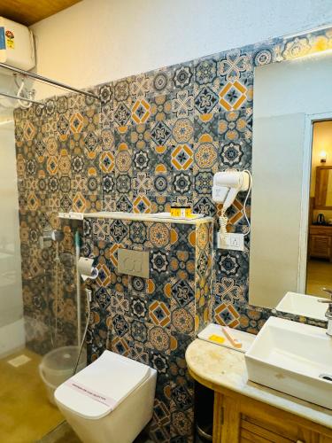 a bathroom with a toilet and a sink and a mirror at Maargit Beach Resort in Mandrem
