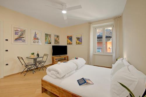 a bedroom with a bed and a tv and a table at Les Suites di Sara 3 and 5 - Happy Rentals in Riva del Garda