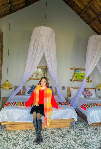 a woman sitting on a bed in a room at Pu Luong Paradise in Hương Bá Thước