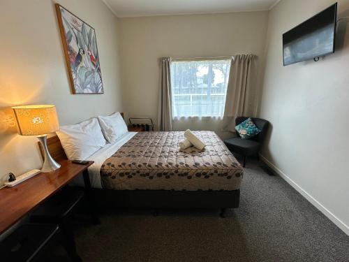 a bedroom with a bed and a desk and a window at Airport Westney Lodge in Auckland