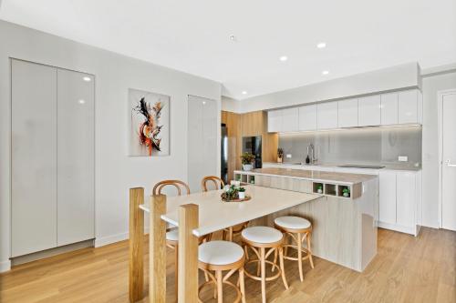 a kitchen with white cabinets and a table and chairs at Bokarina Beach Apartments, an Ascend Collection Hotel in Bokarina