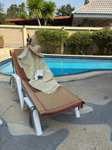 a chair with a blanket sitting next to a swimming pool at Cozy pool villa Cha Am in Ban Sahakham