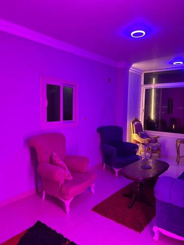 a living room with purple lighting and chairs and a table at شاليهات الهنا 2 للإيجار مصيف قرية النورس الاسماعيلية in Ismailia