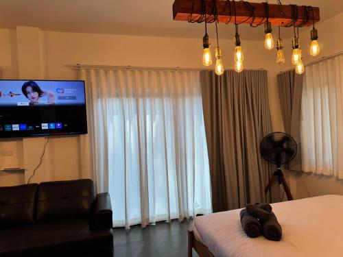 a bedroom with a bed and a flat screen tv at Tanouy Garden in Baan Khai