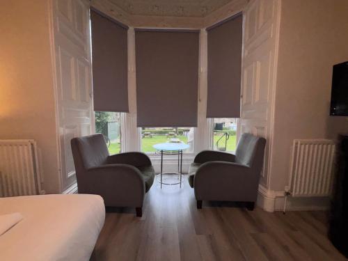 a bedroom with two chairs and a table and windows at No6 West Coates in Edinburgh