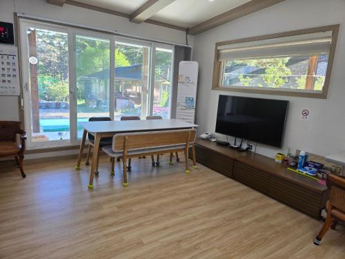 a dining room with a table and a tv at White House Pension in Pyeongchang 