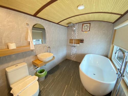 une salle de bain avec une baignoire, des toilettes et un lavabo dans l'établissement UHAUS Train Cabin Resort, à Ban Sai Yok
