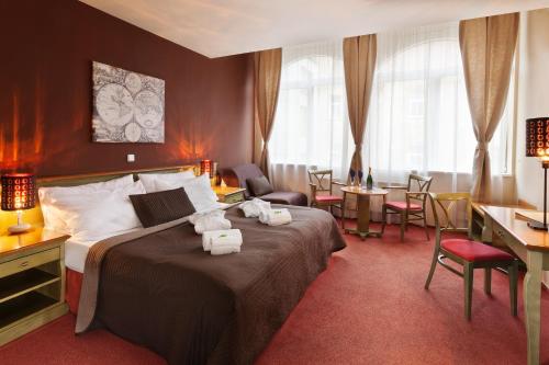 プラハにあるホテル アウグストゥス エト オットのベッド、テーブル、椅子が備わるホテルルームです。