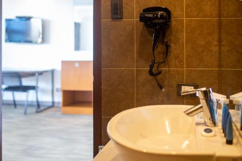 a bathroom with a sink and a phone on a wall at La Breza Hotel in Manila