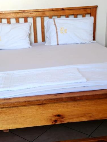 a wooden bed with white sheets and pillows at Mombasa studio in Mombasa