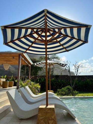 a blue and white umbrella sitting next to a pool at Casa Samudra - charming & spacious villa by the sea surrounded by nature in Selong Belanak