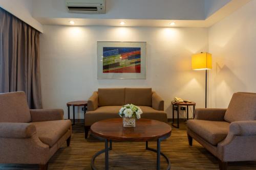 a living room with couches and a table with flowers at La Breza Hotel in Manila