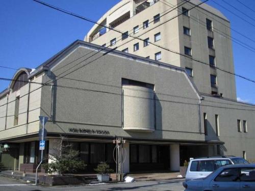 a building with a large building with cars parked in front at HOTEL LiVEMAX Toyooka in Toyooka