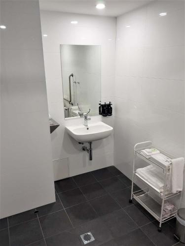 a white bathroom with a sink and a mirror at Mantra Albury in Albury