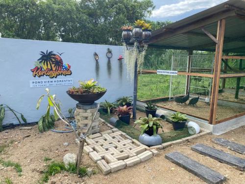 a garden with potted plants and a sign on a wall at Kerlingfornia Pond View Homestay in Kerling