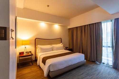 a hotel room with a bed and a large window at La Breza Hotel in Manila