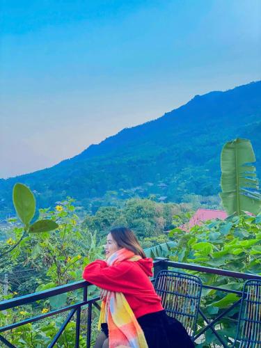 a woman sitting on a balcony looking at the mountains at Pu Luong Paradise in Hương Bá Thước