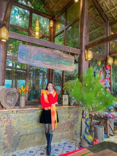 a woman is standing in front of a building participation sign at Pu Luong Paradise in Hương Bá Thước
