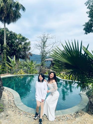 two women standing in front of a swimming pool at Pu Luong Paradise in Hương Bá Thước