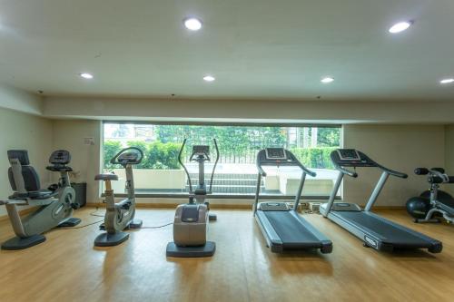 a gym with cardio machines and a large window at La Breza Hotel in Manila