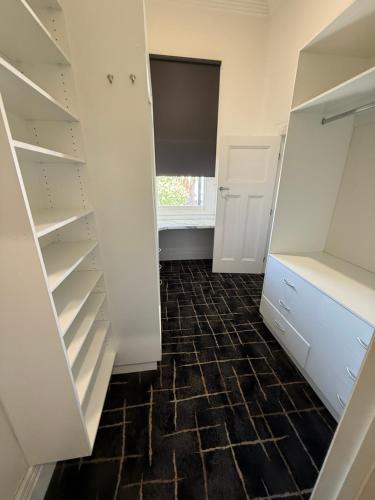 a walk in closet with white cabinets and a tile floor at The Loft Cobram Hotel in Cobram