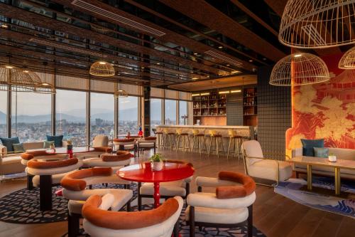 a lobby with tables and chairs and windows at Mercure Kathmandu Sukedhara Heights in Kathmandu