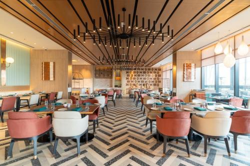 a dining room with tables and chairs and windows at Mercure Kathmandu Sukedhara Heights in Kathmandu