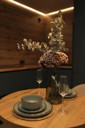 a table with plates and a vase with flowers and glasses at Элитные 2-комн Апартаменты Дарк Сьют in Petropavlovsk