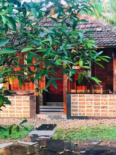 a tree in front of a building with a door at Karmaliz Casa Del Lake in Chavara