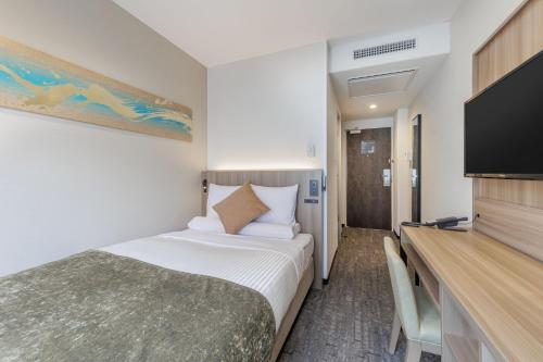 a hotel room with a bed and a flat screen tv at HOTEL MYSTAYS Kanazawa Katamachi in Kanazawa