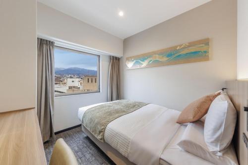 a bedroom with a bed and a large window at HOTEL MYSTAYS Kanazawa Katamachi in Kanazawa