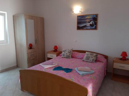 a bedroom with a bed with a pink bedspread at Apartments Franka Saplunara-One-Bedroom Apartment with Terrace and Sea View No1 in Saplunara
