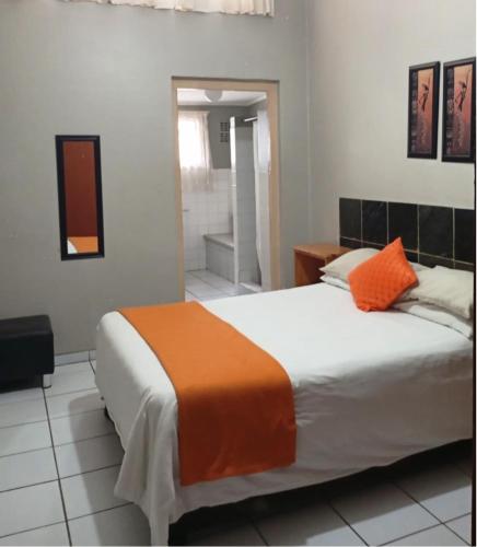 a bedroom with a bed with an orange blanket on it at The Airport Lodge - East London in East London
