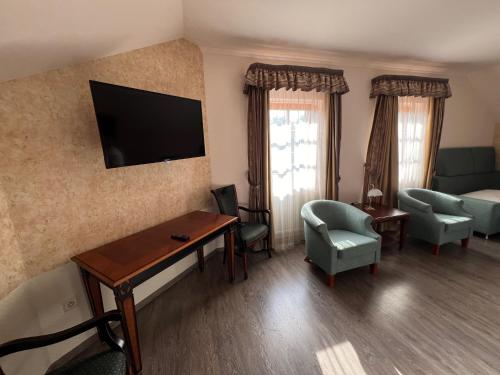 a living room with a couch and a tv on the wall at Hotel Gold Chotoviny in Chotoviny