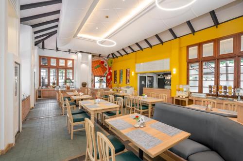 a restaurant with wooden tables and chairs and yellow walls at Sunshine Garden Resort in North Pattaya