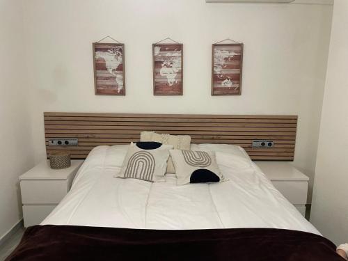 a bedroom with a large white bed with three pictures on the wall at Bonito apartamento en Aguadulce in Aguadulce