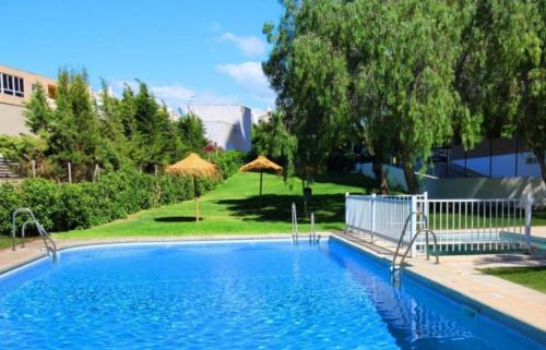 a large blue swimming pool in a yard with trees at Bonito apartamento en Aguadulce in Aguadulce