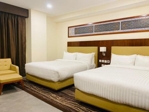 a hotel room with two beds and a chair at Avari Boutique Gujranwala in Fattu Mand