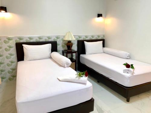 two beds in a hotel room with flowers on them at SUAN SANG CHAN RIVERSIDE Resort สวนแสงจันทร์ ริเวอร์ไซด์ รีสอร์ท in Ban Bang Khoi