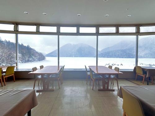 a restaurant with tables and chairs and a large window at Shikaribetsu Kohan Onsen Hotel Fusui in Shikaoi