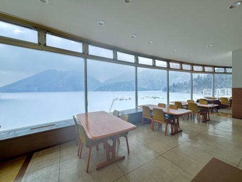 a room with tables and chairs and a large window at Shikaribetsu Kohan Onsen Hotel Fusui in Shikaoi