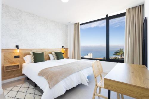 a bedroom with a bed and a table and a large window at Gorvorana 3 - Piscina privada, BBQ in Realejo Bajo