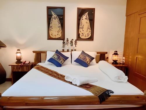 a bedroom with a bed with white sheets and blue pillows at SUAN SANG CHAN RIVERSIDE Resort สวนแสงจันทร์ ริเวอร์ไซด์ รีสอร์ท in Ban Bang Khoi